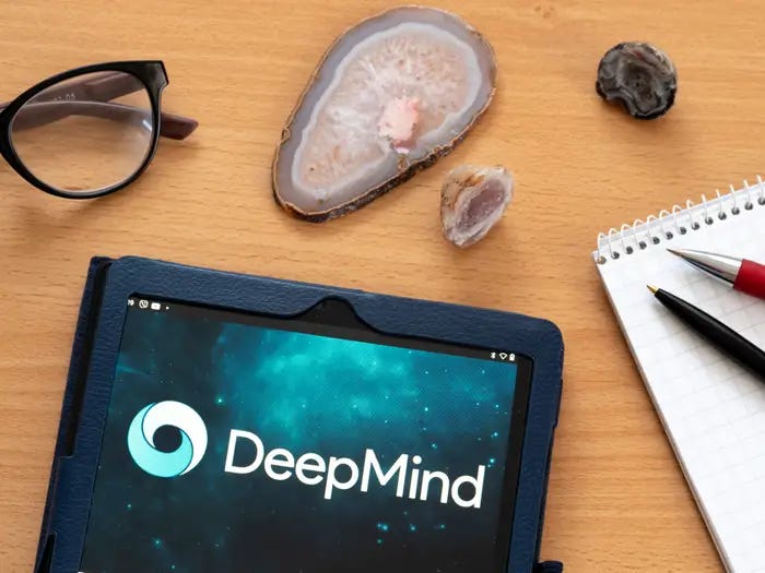 Cristais em uma mesa ao lado de um oculos, cardeno e um tablet exibindo o logo do DeepMind do Google