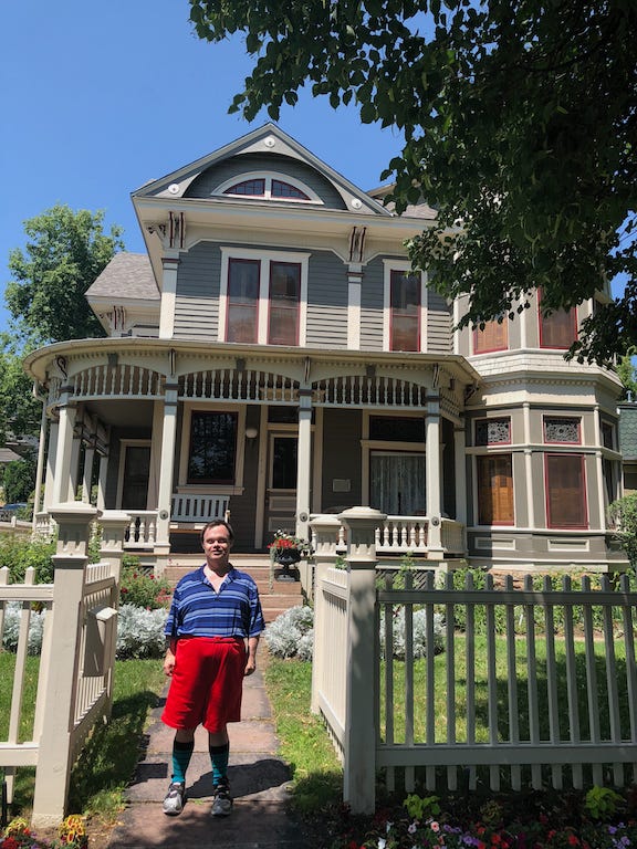A man standing in front of a Victorian style home in Boulder, Colorado