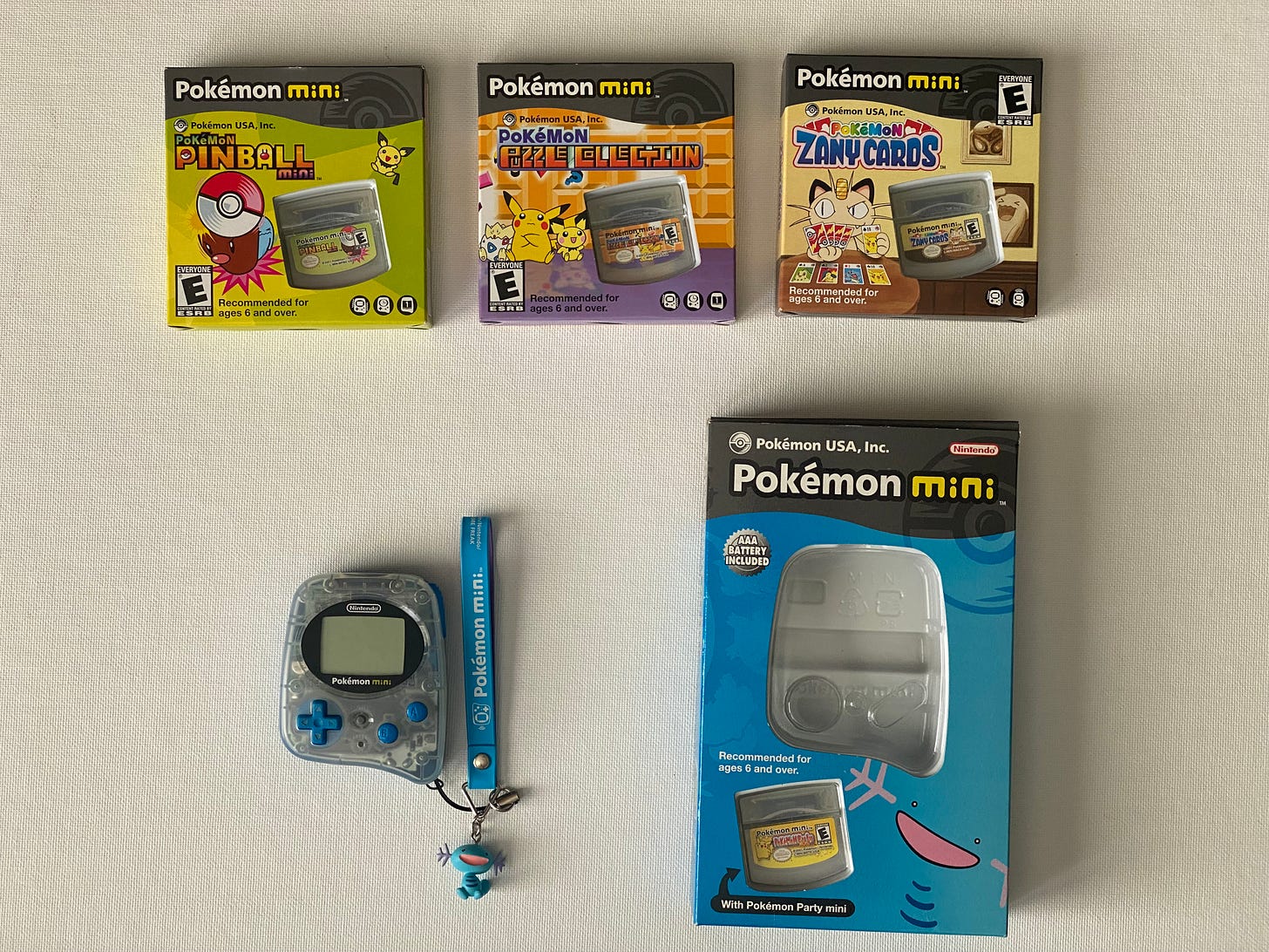 Tatton’s Pokémon Mini (Wooper Blue) and games, which include Pokémon Party Mini, Pokéball Pinball Mini, Pokémon Puzzle Collection, and Pokémon Zany Cards. The Pokémon Mini also has a Wooper key charm attached to it