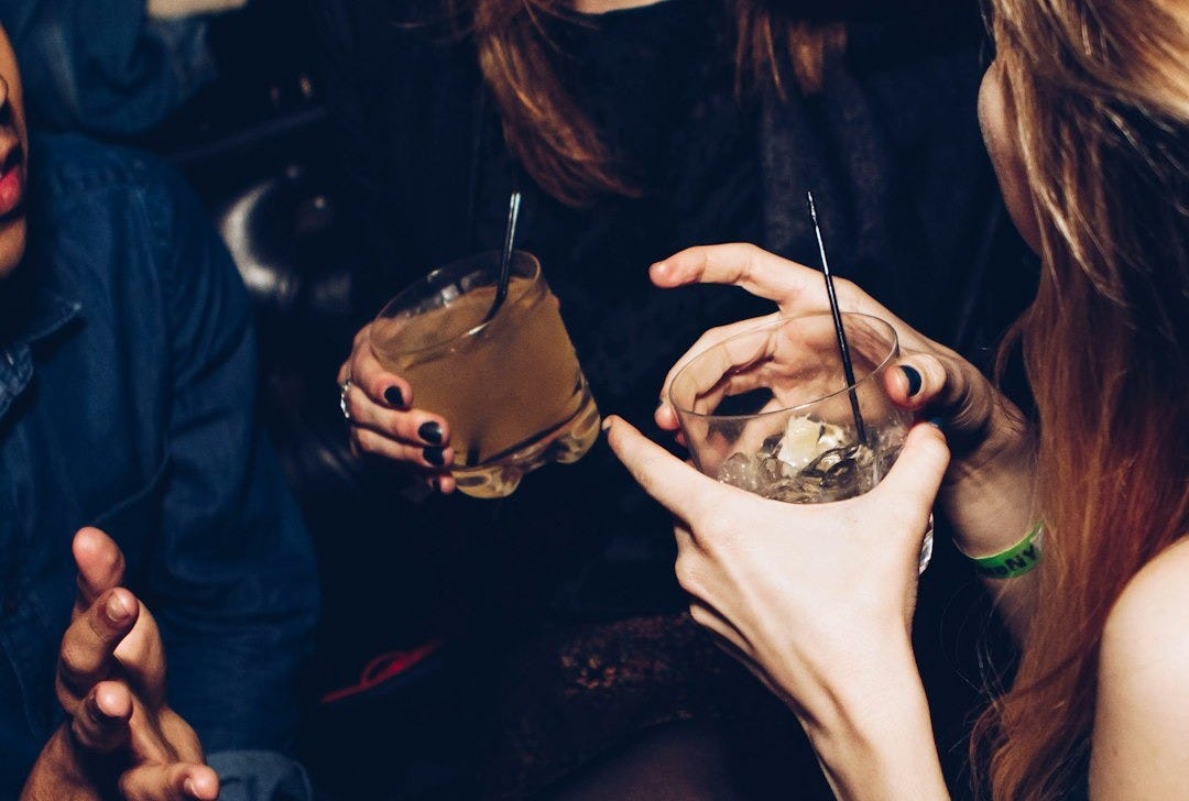 two women talking while holding drinking glasses two women talking while holding drinking glasses