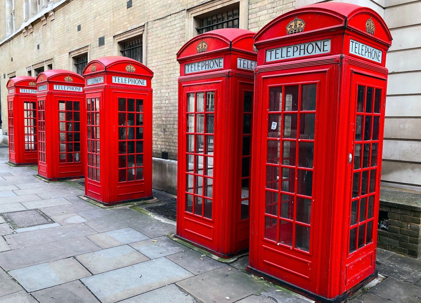 A London street scene with five red telephone boxes in a line.