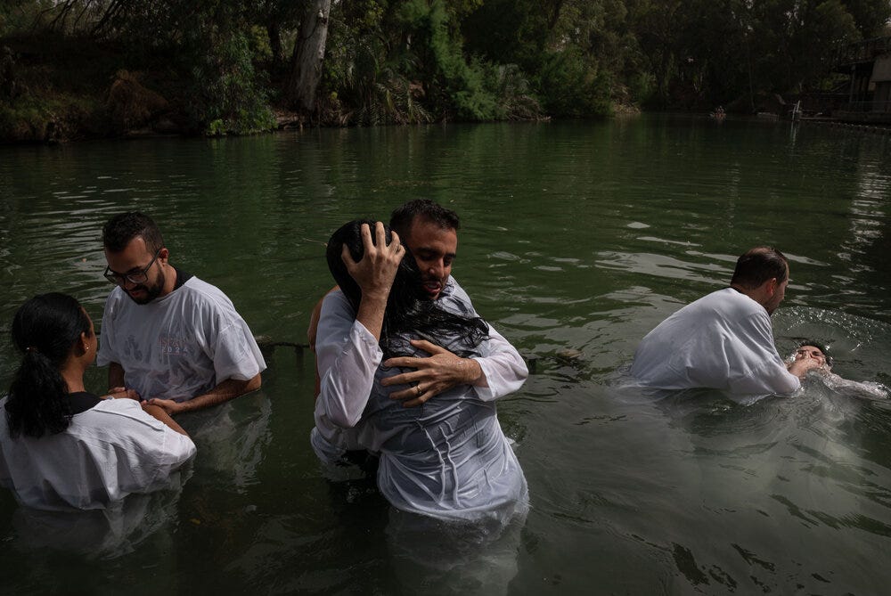 Evangelicals from Brazil wade, pray and get baptized in the Jordan river in Israel.