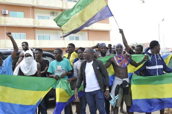 Residents holding Gabon national flags celebrate.