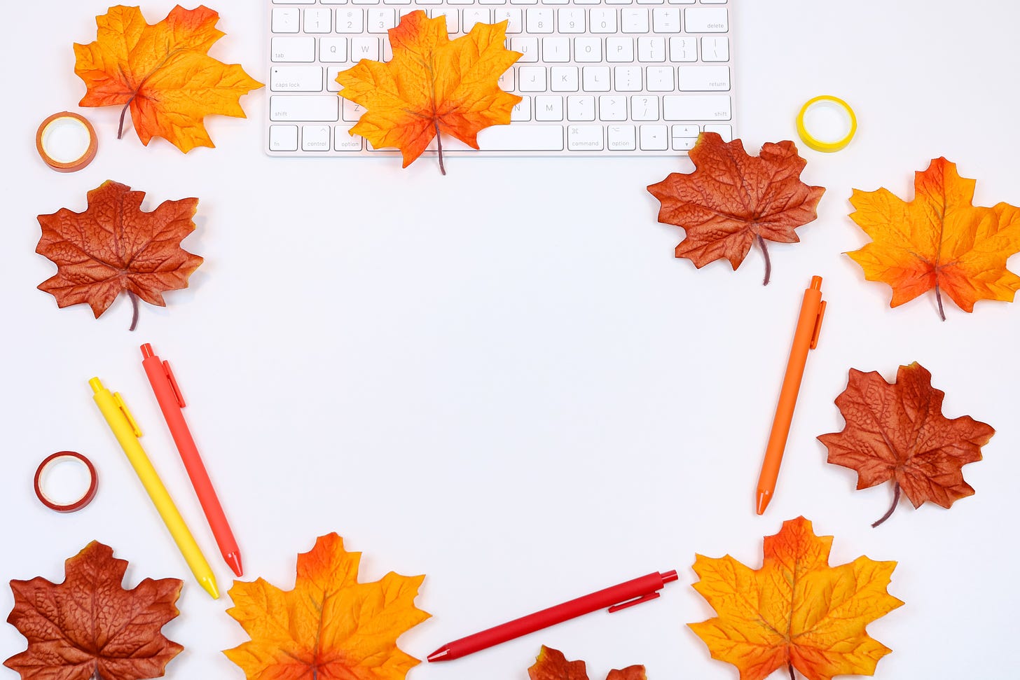 autumn leaves, pens in autumnal colors, and a computer keyboard