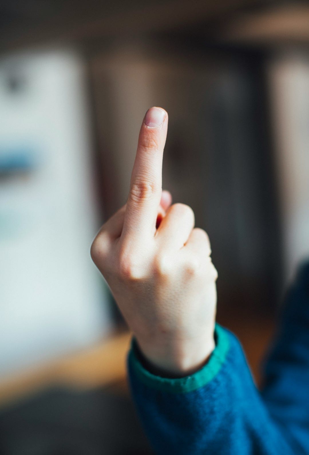 person in blue long sleeve shirt showing right middle finger