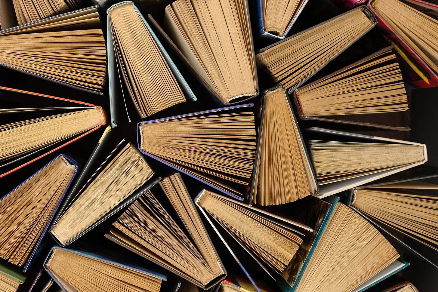 An image of several books seen from above. The books are all fanned open and positioned at different angles within the frame.