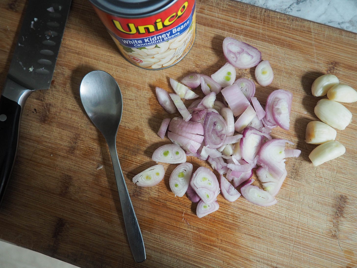 Reference photo for those working without a scale. This is approximately 4-5 small shallots and 5 large cloves of garlic. The spoon is an average tablespoon for scale.