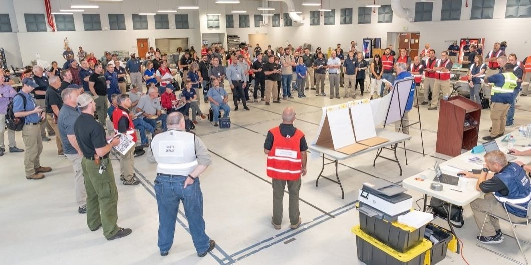 A vast group of individuals gather at a large facility, actively participating in civil defense training, showcasing a nation's commitment to preparedness, safety, and resilience.