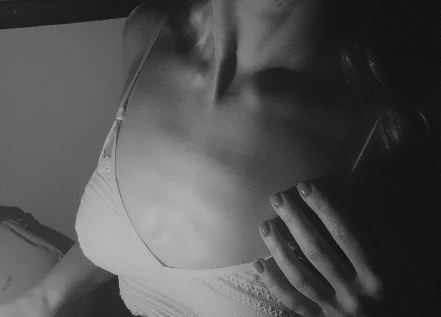 Black and white photo of a woman's neckline and a white bra