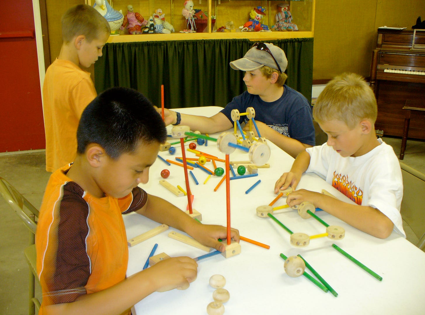 Four boys focus on building their projects with Tinker Toys during summer arts classes.