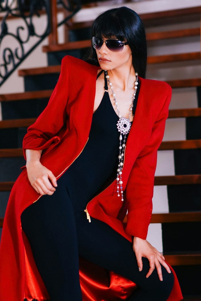 Model in a black dress and a long red coat.
