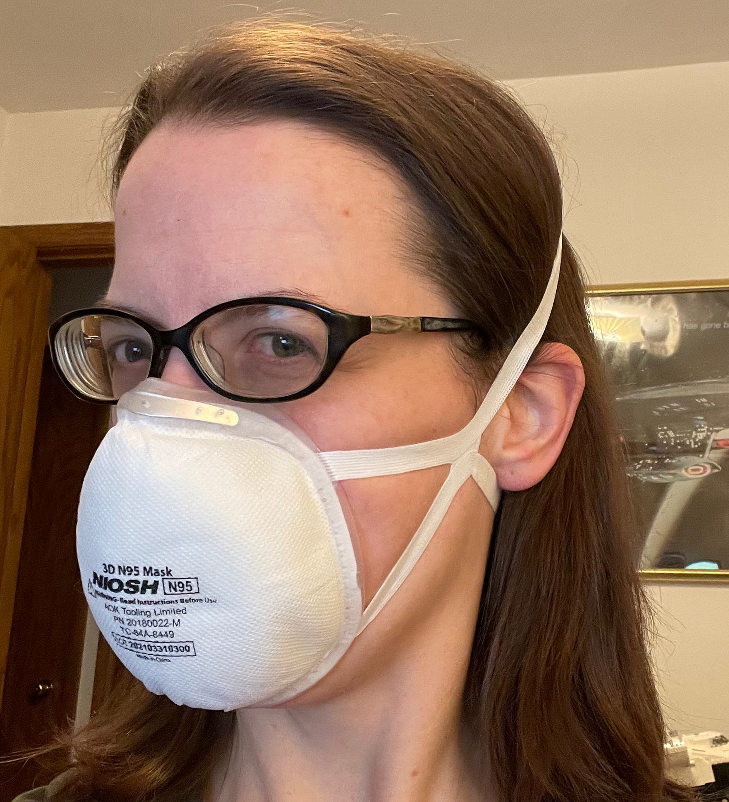 Woman wearing glasses and a cup-shaped N95 respirator