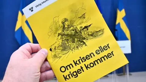 TT News Agency/AFP A hand holding a yellow booklet in front of Swedish flags - it has the words 'Om krisen eller kriget kommer' on the front and an illustration of soldiers and a family 