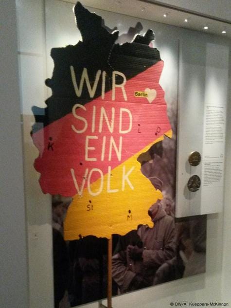 The "Wir sind ein Volk" slogan on a yellow, red, and black map of Germany