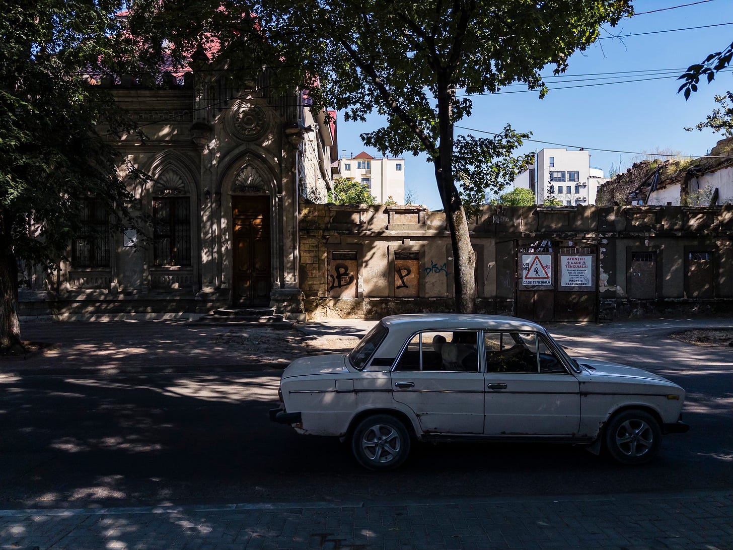 an old car in front of a derelict building in the streets of Chisinau, Moldova