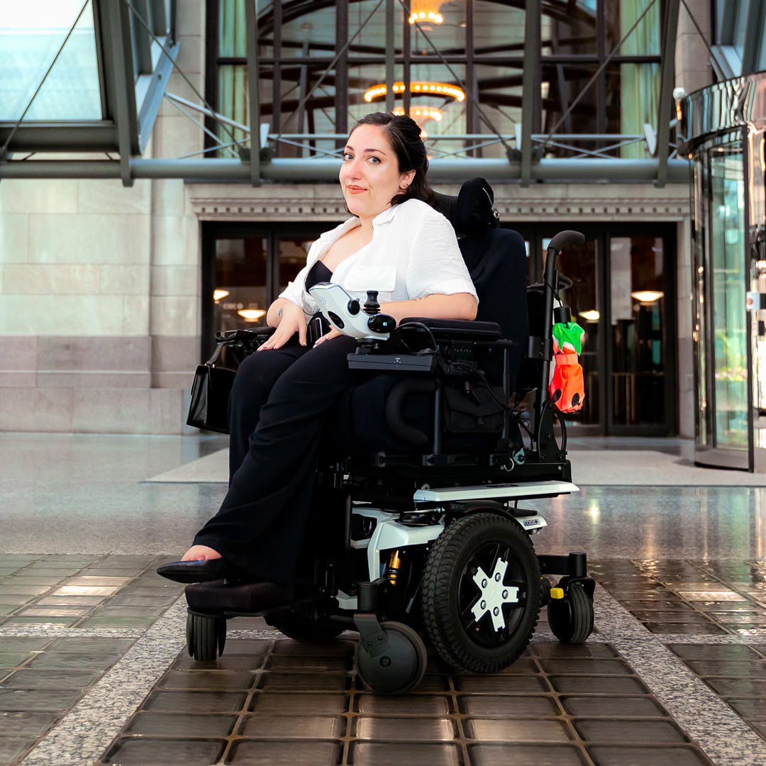 Jessica Oddi sitting in her power wheelchair. She is looking fierce and stylish.