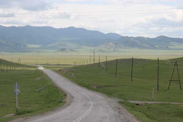 Road going into distance with telephone poles and grassy hills