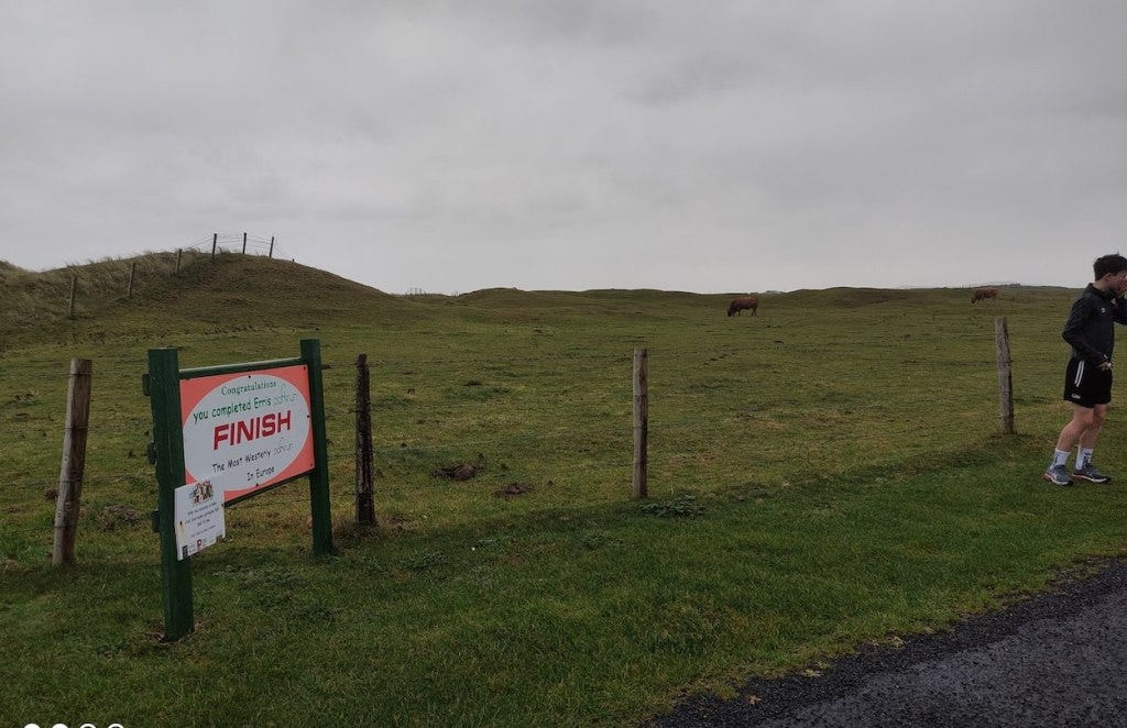Cows graze in the field behind the finish, while a permanent sign marks the spot