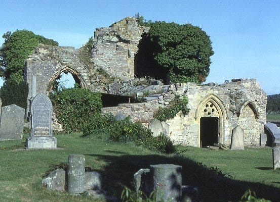 A ruined abbey, partly overgrown, with later gravestones in the foreground
