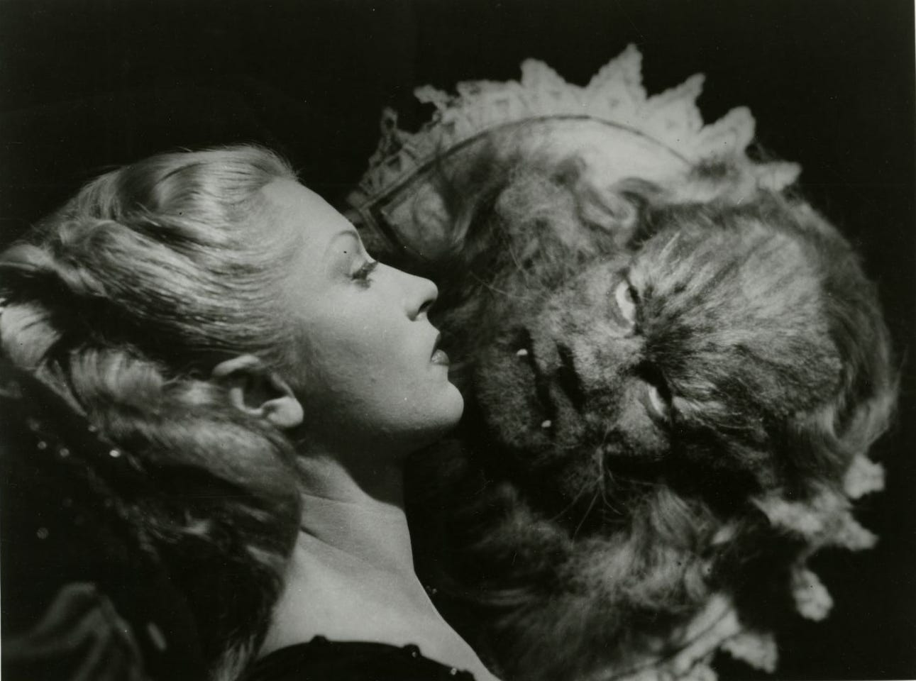 Black and white phorograph showing a blonde-haired woman in profile, facing a hairy beast in the shape of a man