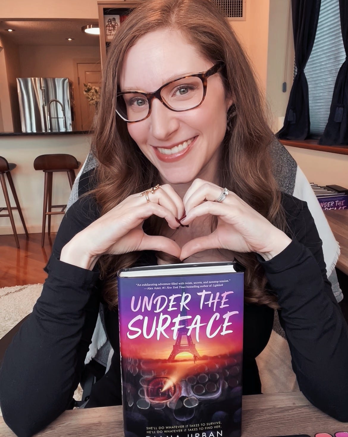 Diana Urban doing heart hands over a copy of Under the Surface