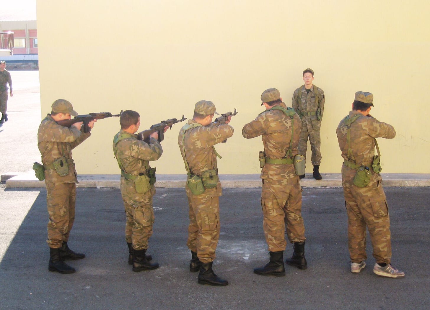 cypriot conscripts performing a mock execution of another soldier against a wall