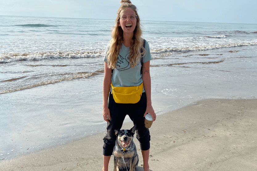 Scout the Australian cattle dog posing between her owner's legs on the dog-friendly section of Cocoa Beach in Florida