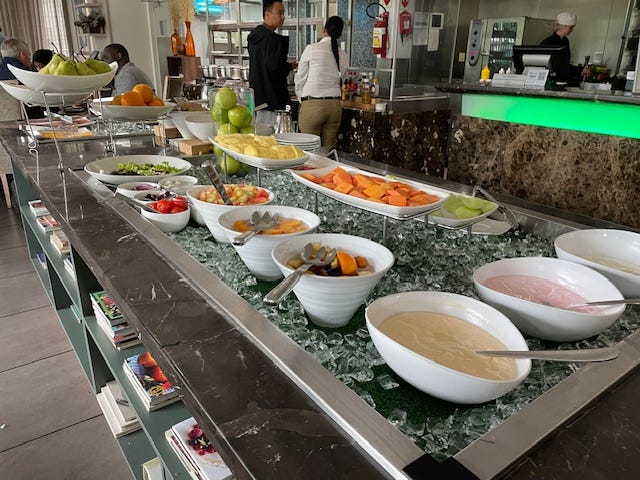 A counter displaying many bowls of fruit and other food