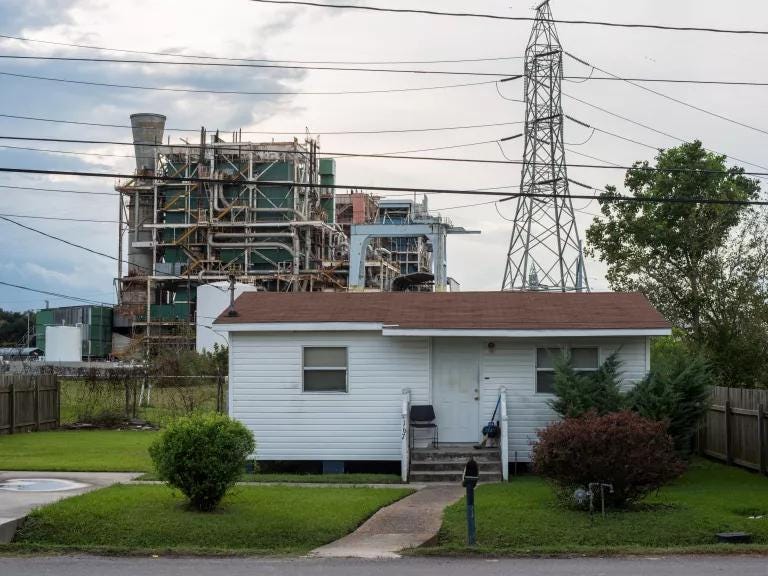 A house sits in the forefront of an electrical tower and a chemical plant. A house sits in the forefront of an electrical tower and a chemical plant.
