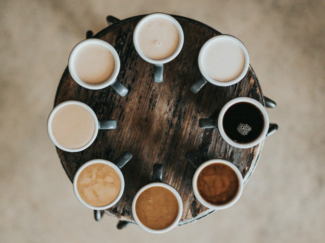flat lay photography of eight coffee latte in mugs on round table flat lay photography of eight coffee latte in mugs on round table