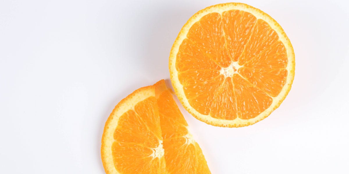 Foto de uma laranja cortada sobre fundo branco.