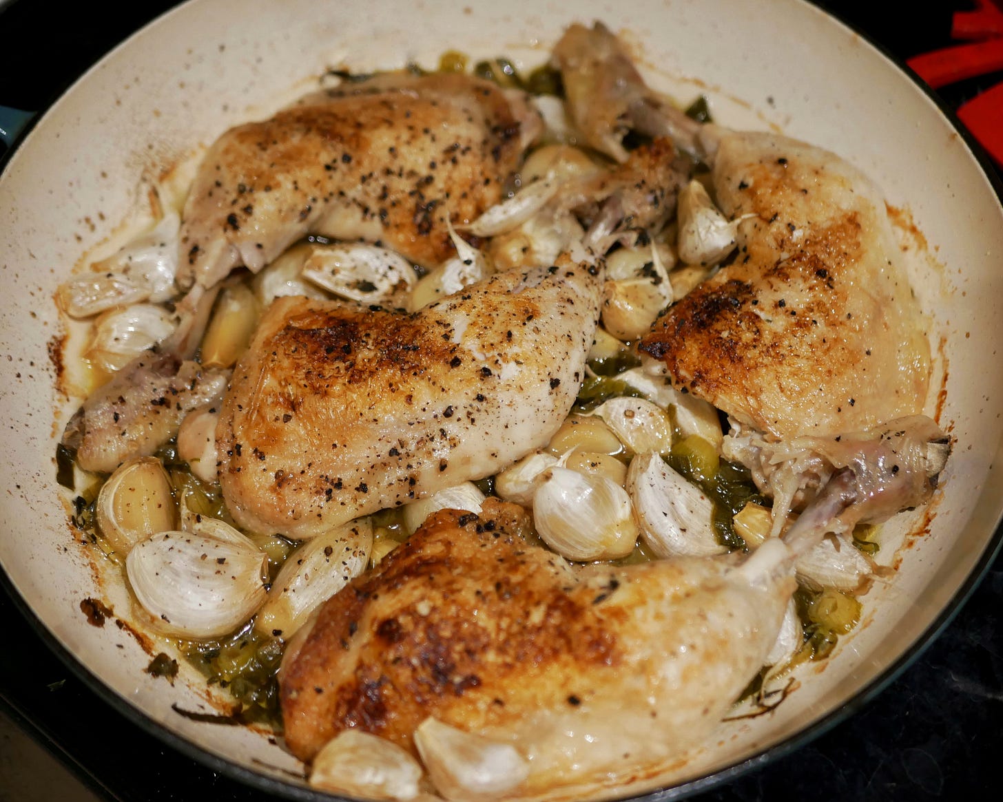 A photo of 40 Garlic Clove Chicken Legs in a wide, low dutch oven.