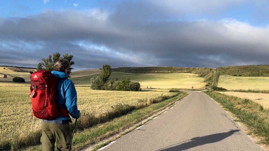 I'm seen on the back, walking the Camino de Santiago in a wide open landscape