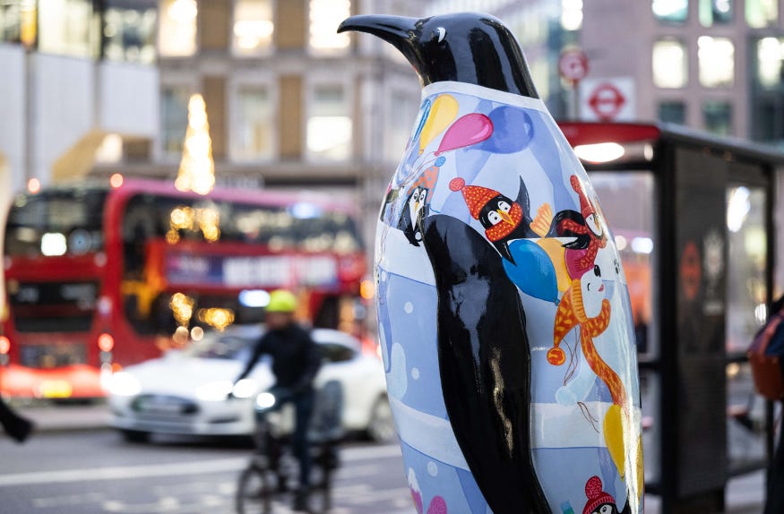 A penguin statue, decorated with images of penguins skiiing