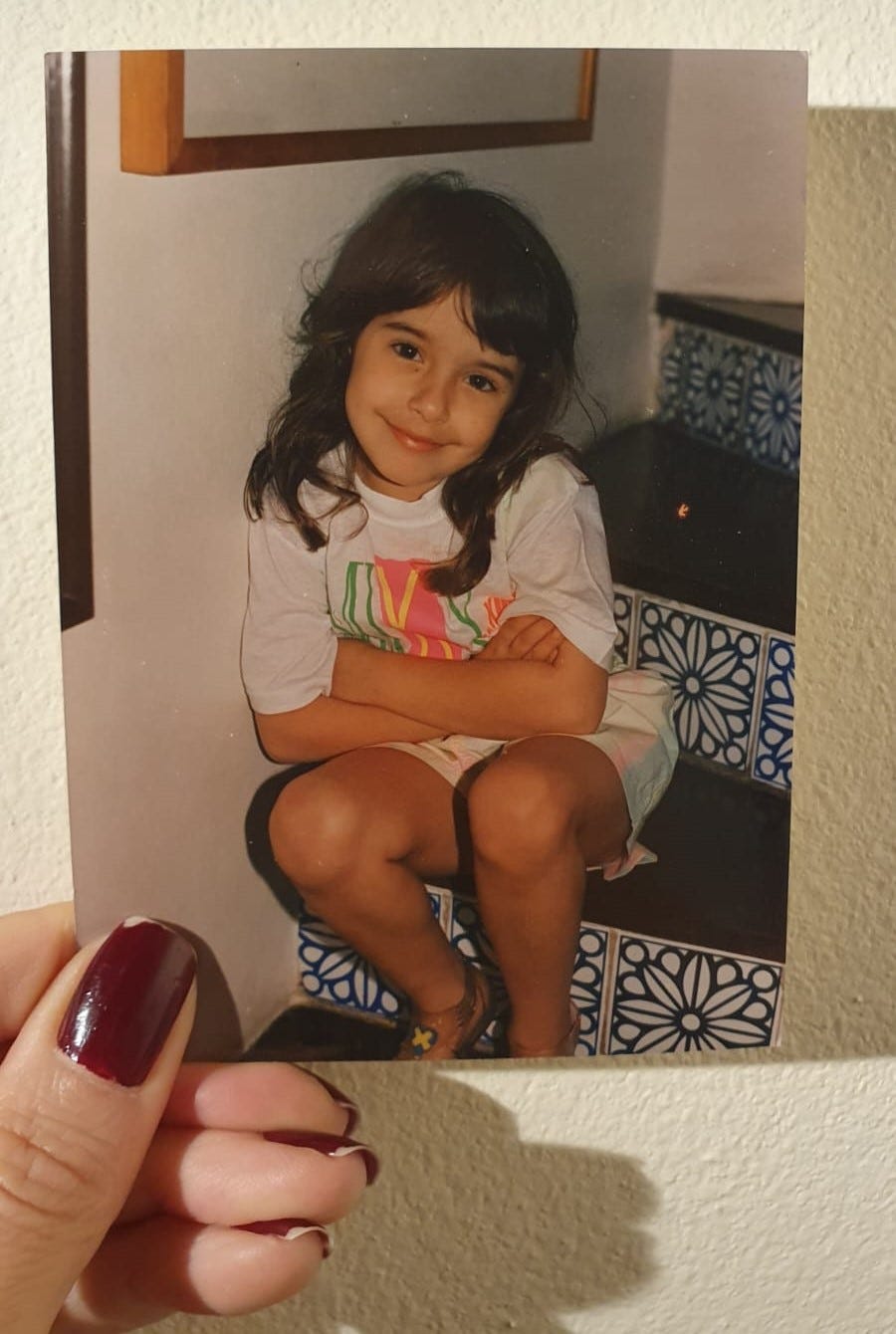 Uma fotografia minha com cerca de 6 anos sentada na escada de casa