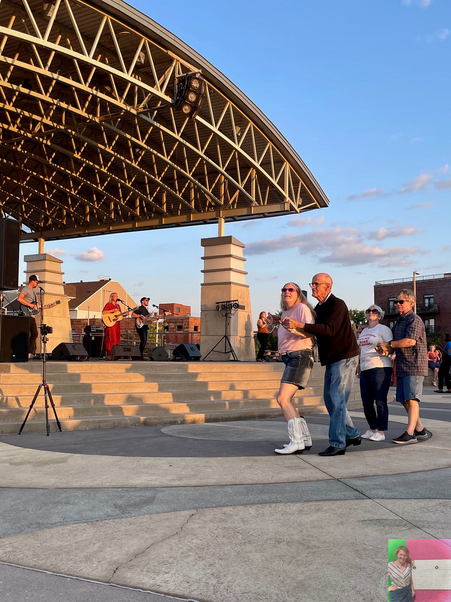 people line dancing in front of the stage at an outdoor concert