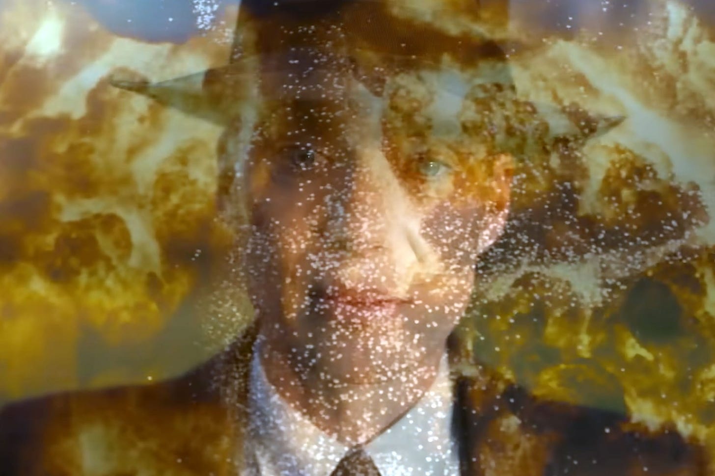 Portrait shot of Cillian Murphy as J. Robt. Oppenheimer in fedora and suit, melded with the image of a nuclear explosion in molten golds and browns