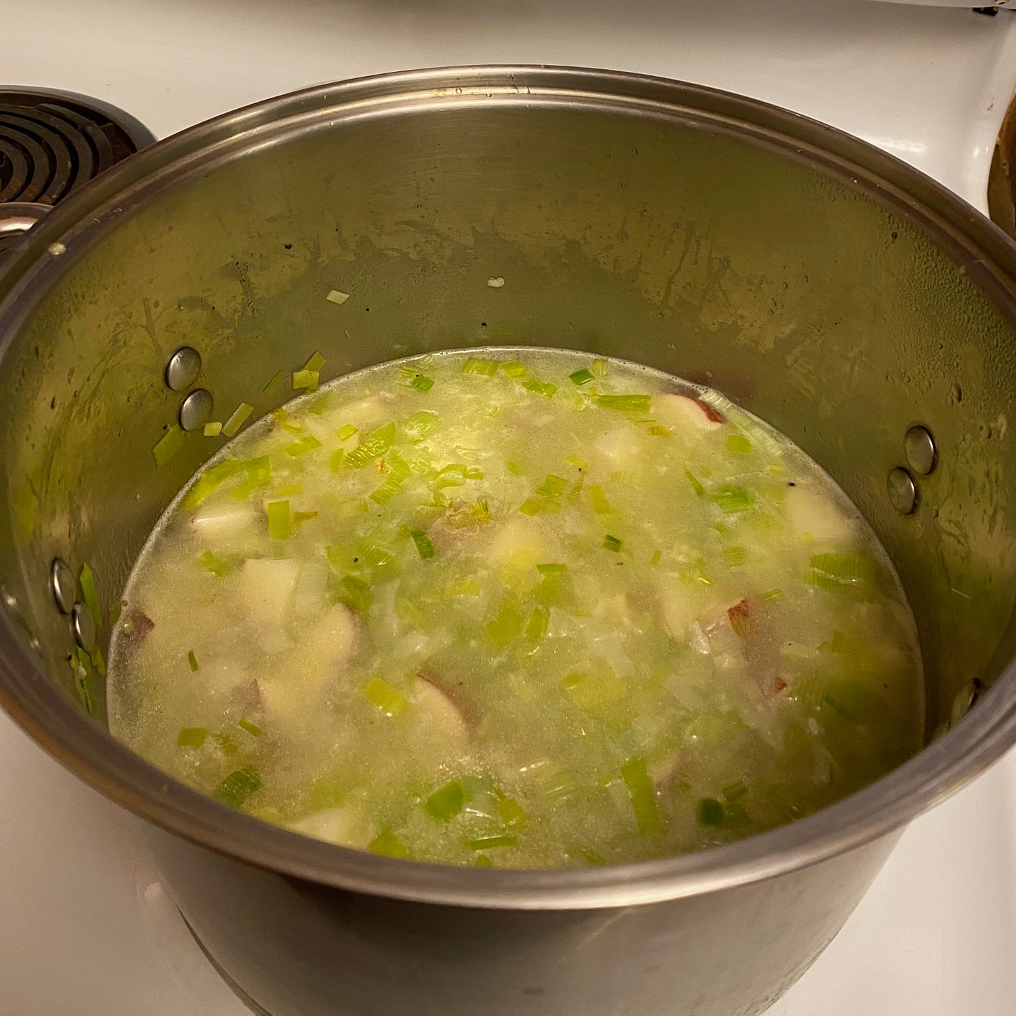 A pot of potato leek soup simmer on the stove.