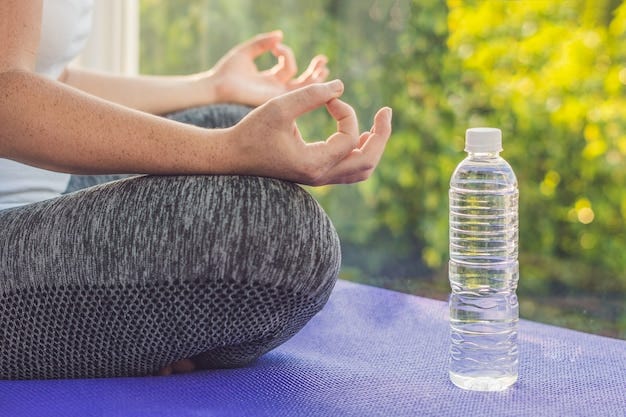 Hand of a woman meditating in a yoga pose on a rug and a bottle of water