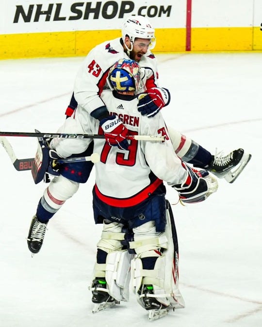A picture of hockey player Tom Wilson excitedly embracing Capitals goalie after clinching a spot in the playoffs. 