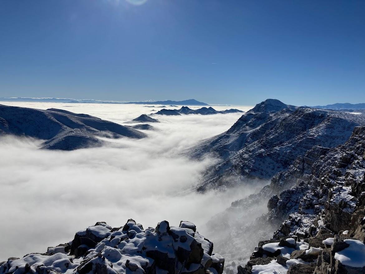 A snowy mountain range with clouds

Description automatically generated