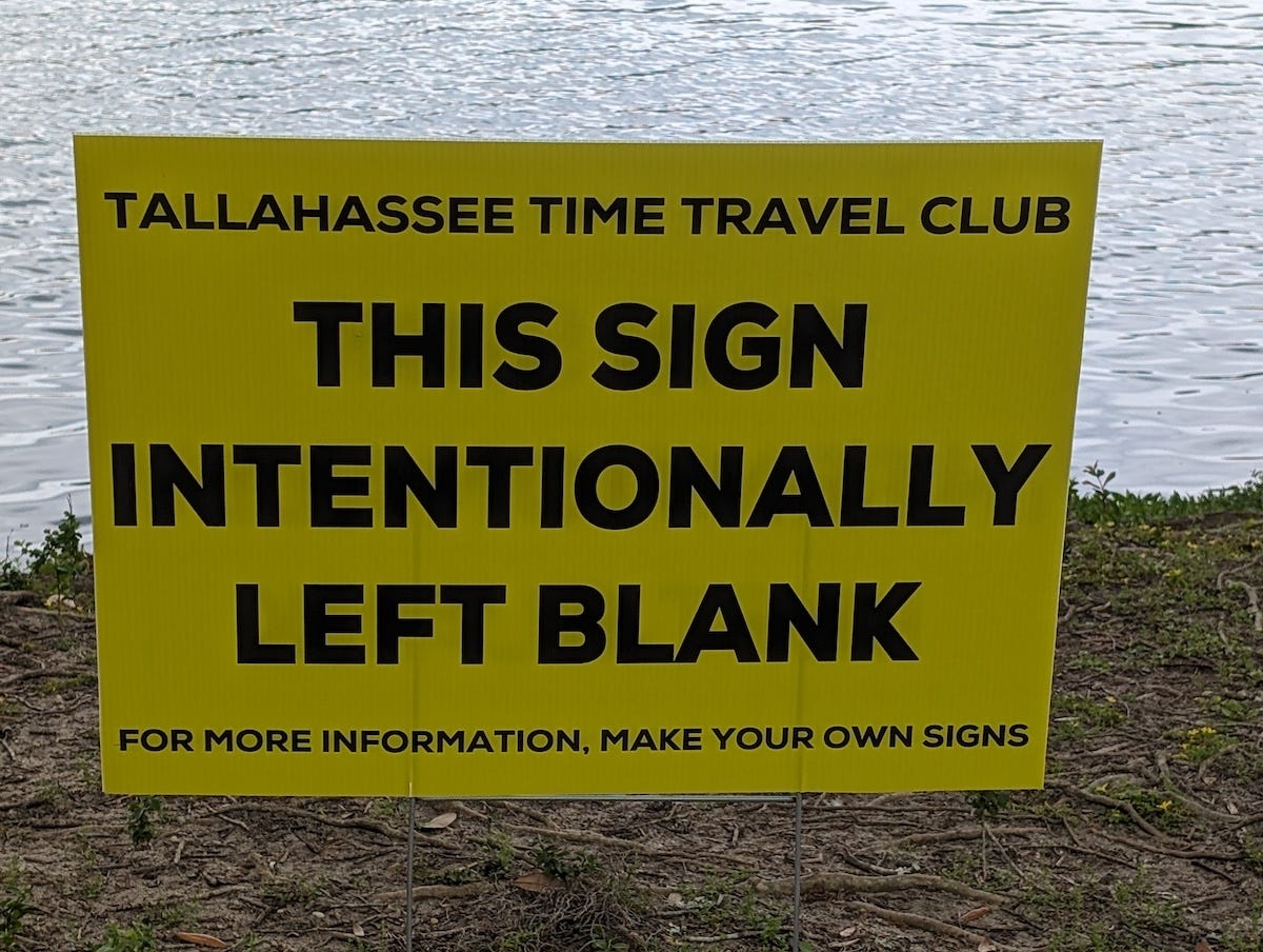Sign post next to a public walkway: "this sign intentionally left blank. For more information, make your own signs."