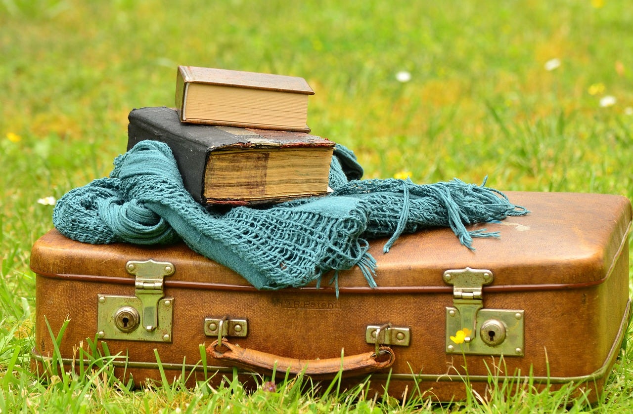 Closed suitcase with shawl and books on top