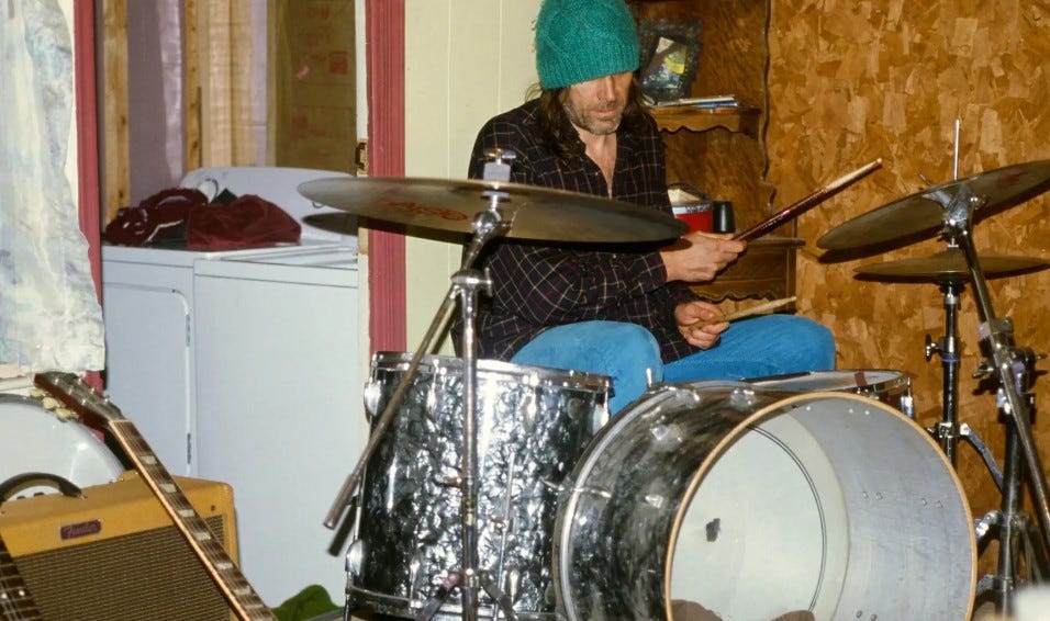 Evan Dando in hat playing drums.
