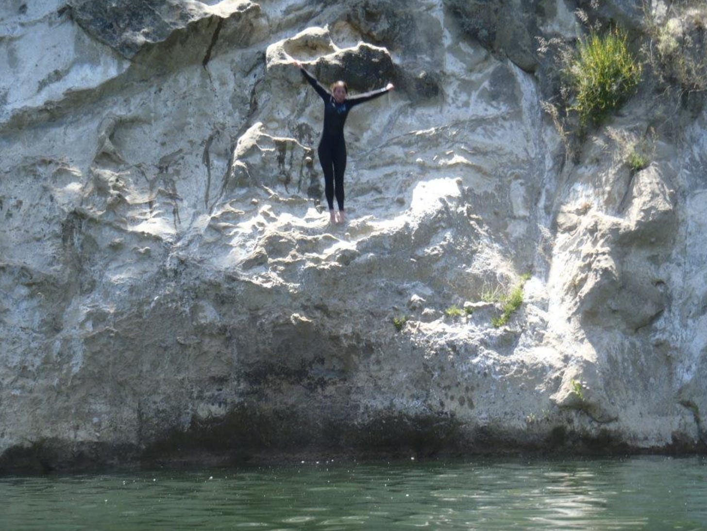 A woman jumping into a river from a rocky ledge