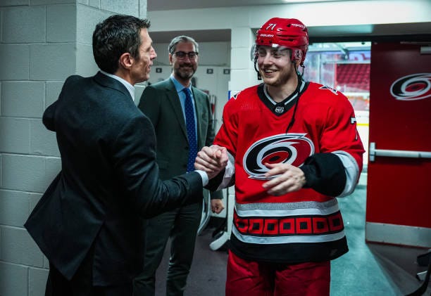 Jesper Fast of the Carolina Hurricanes greets head coach Rod Brind'Amour in the locker room after scoring the game-winning goal in overtime against...