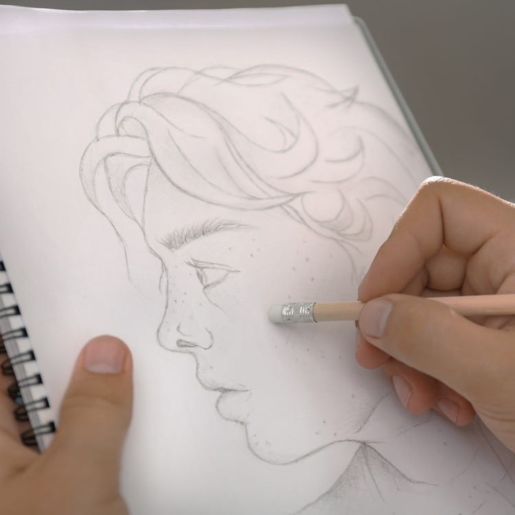 Artist erasing pencil lines representing writers rewriting.