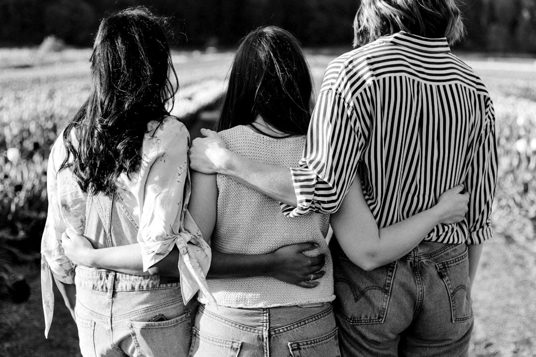 three women holding hand in front of flower garden three women holding hand in front of flower garden