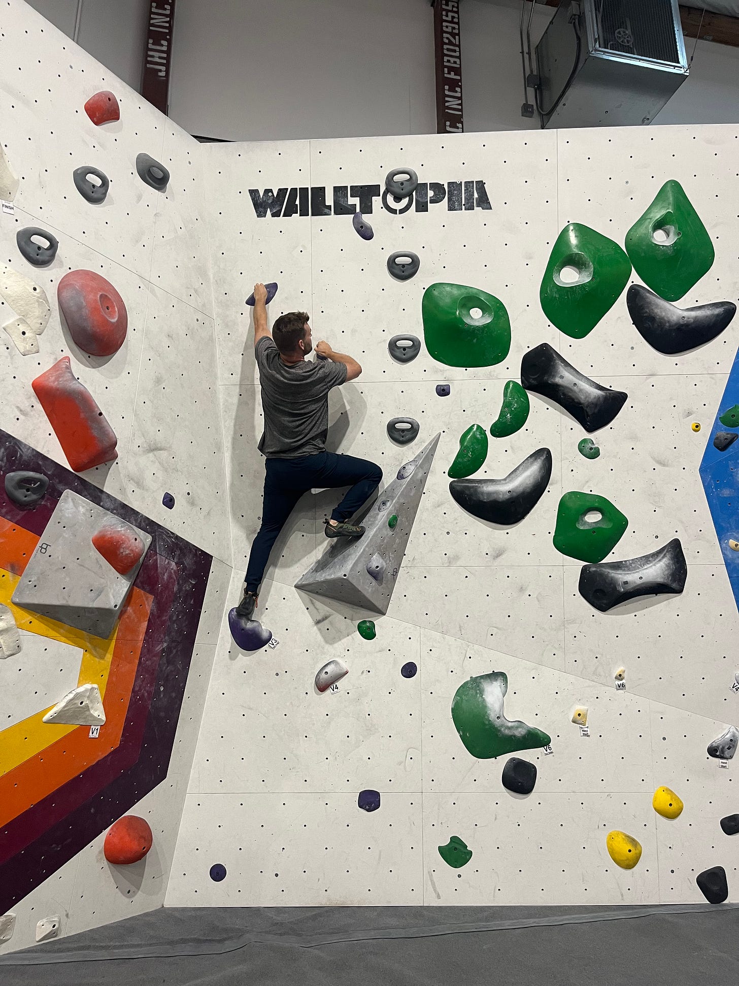 A man scaling a climbing gym wall