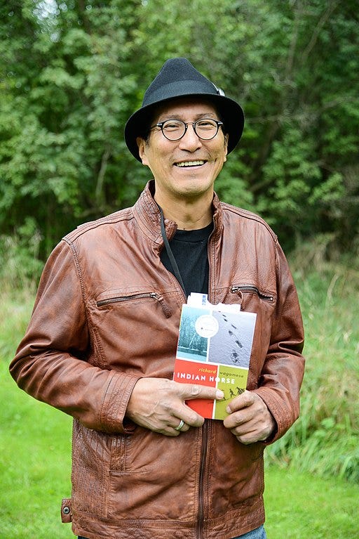 Richard Wagamese holds Indian Horse and smiles into the camera.